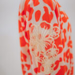 Close up fabric detail of orange and white abstract leopard print shirt