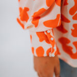 Sleeve cuff detail of orange and white abstract leopard print shirt
